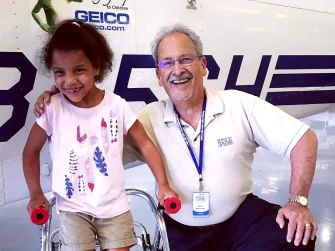 Dick with young patient, Elizabeth, in front of the Wings of Hope plane before her flight home.